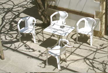 Plastikstühle vorm Kafenio und Schatten des Weines, der noch nicht ausgetrieben hat.